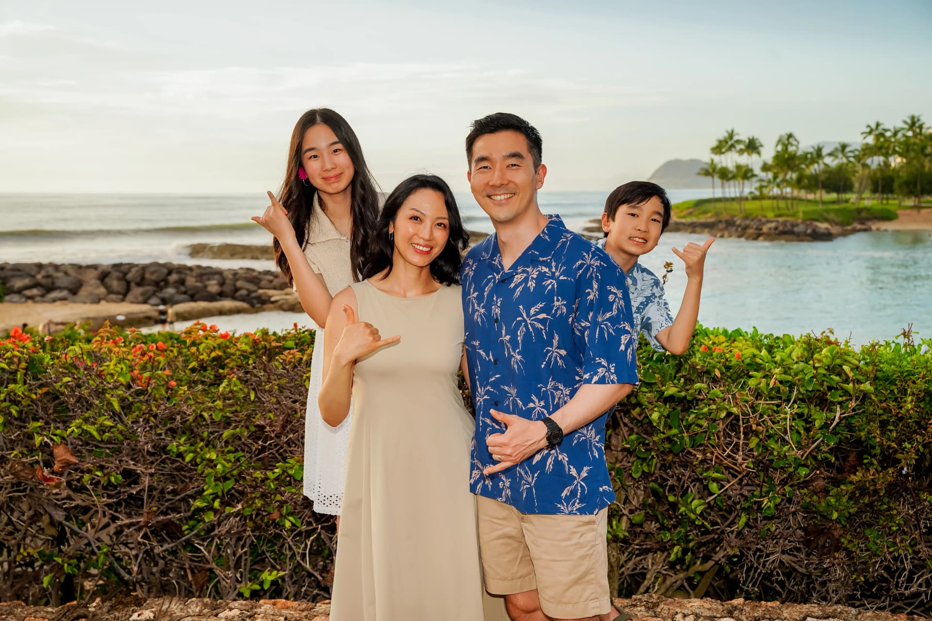 Family of four with shaka sign by the ocean at sunset